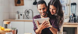 A couple uses a tablet to research homes for sale.